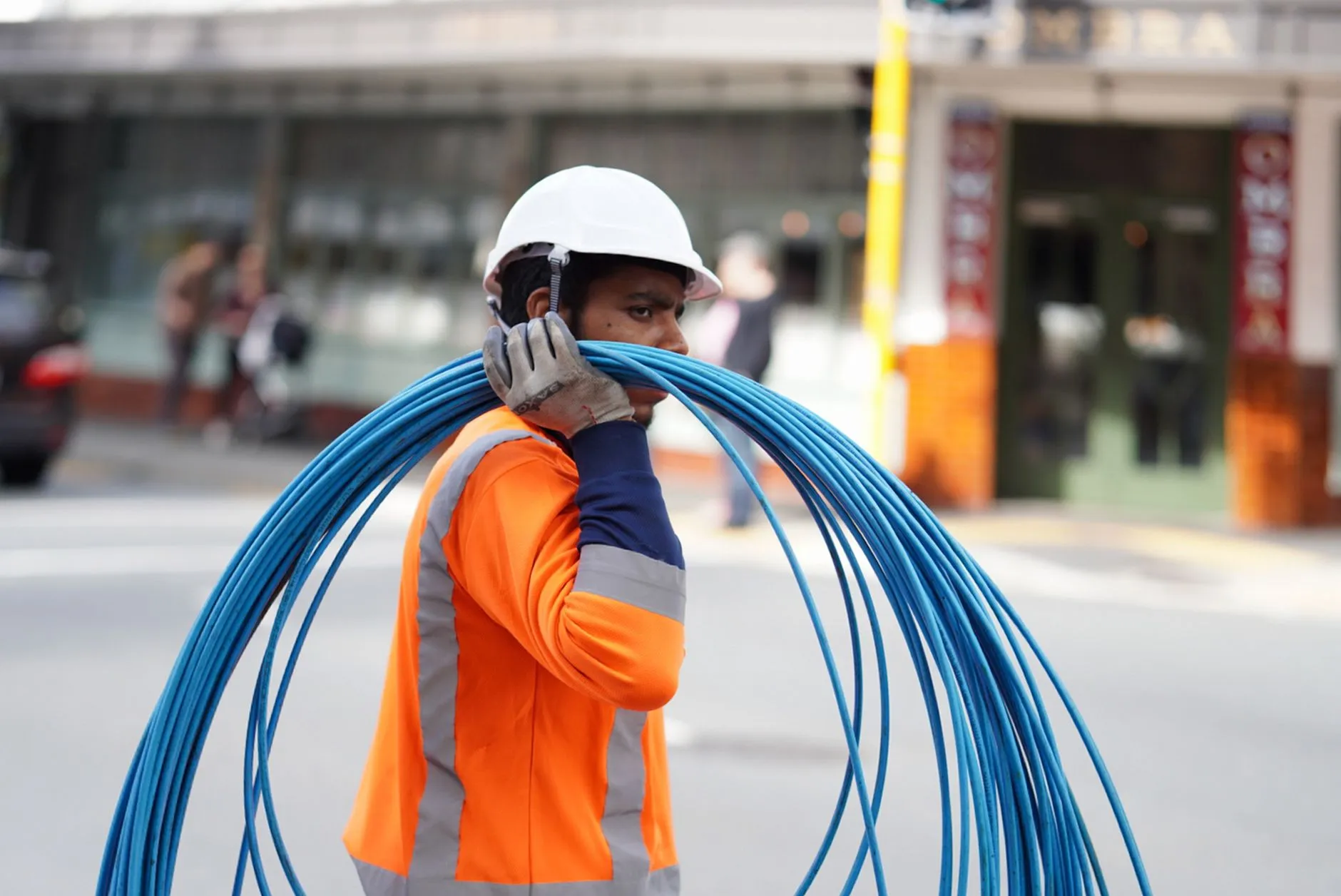 Worker carrying cables on a street.