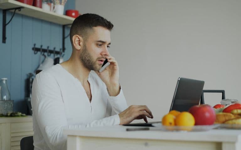 Man on the phone to his provider with a laptop open at the table